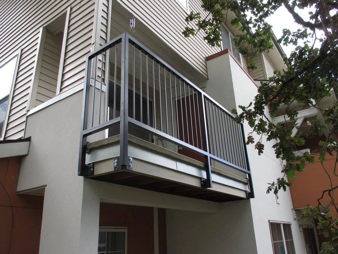 A balcony with metal railing and white walls.