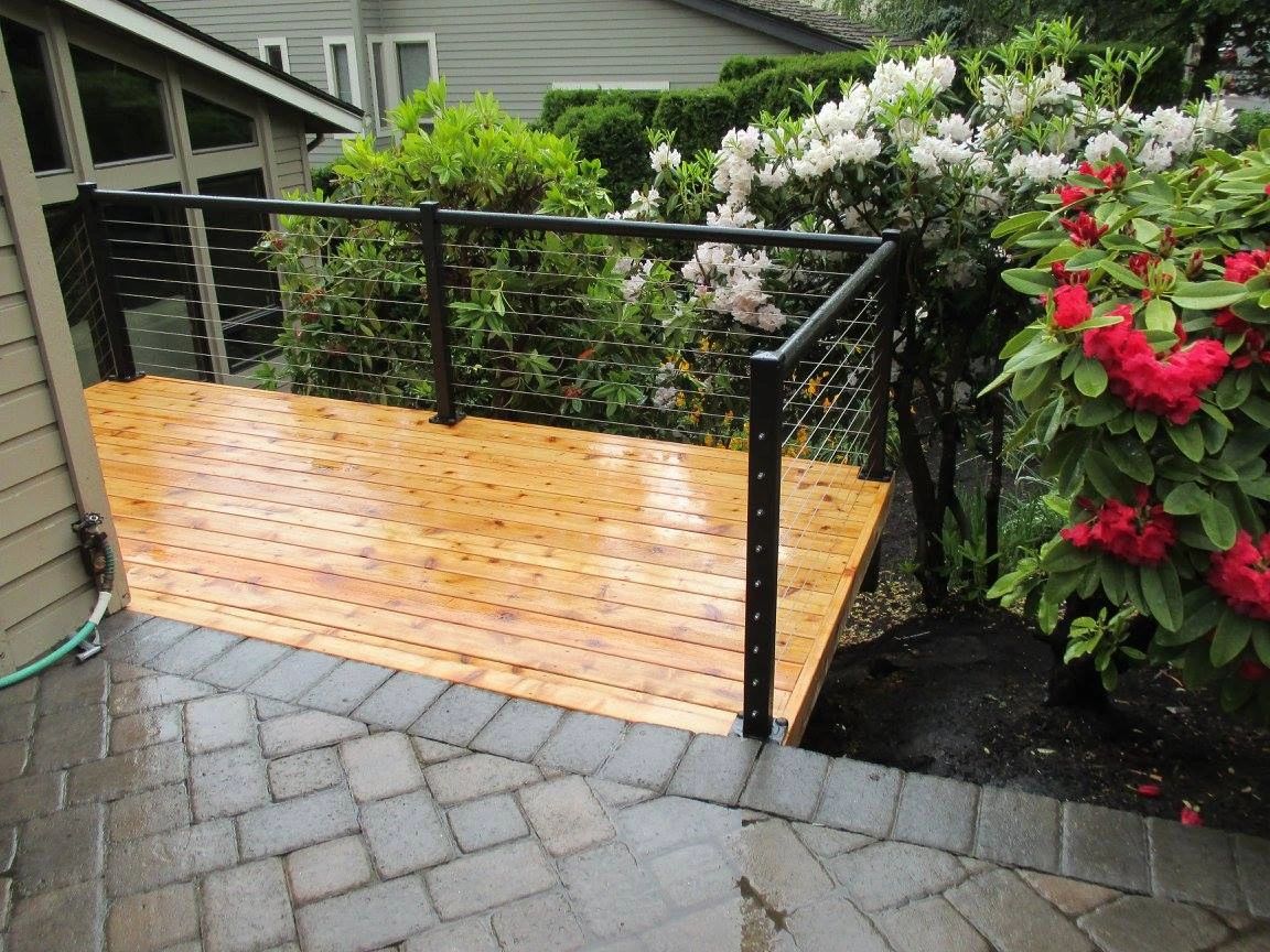 A wooden deck with metal railing and flowers.