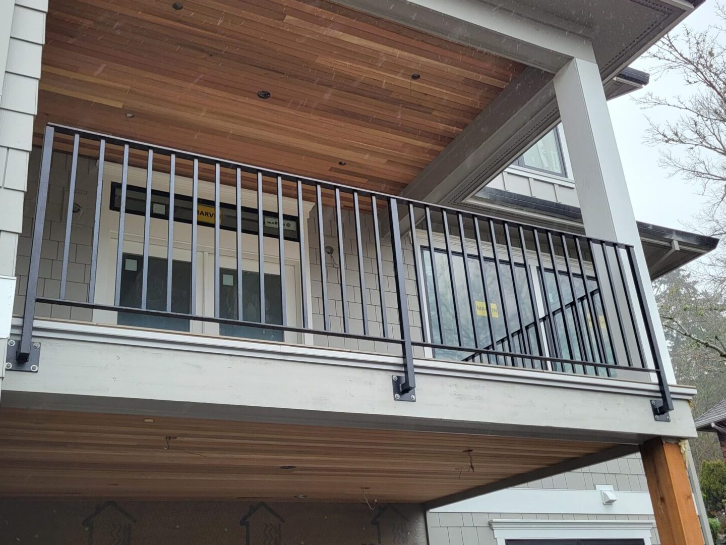 A balcony with metal railing and wood ceiling.