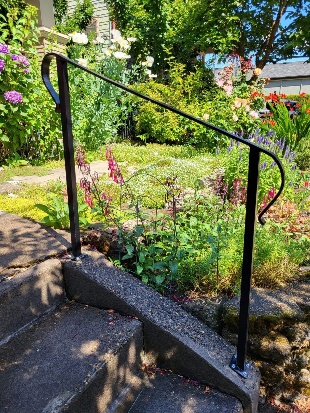 A metal railing in the middle of a garden.