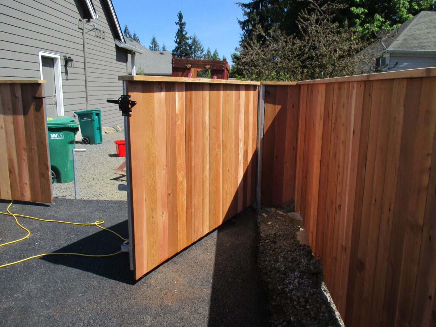 A wooden fence with a gate open on the side.