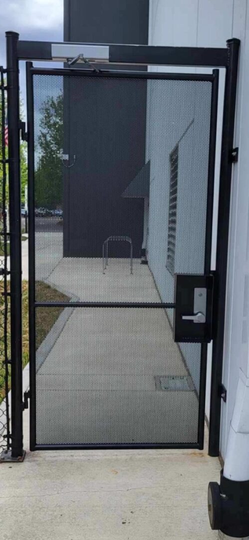 A black metal gate with a glass door.