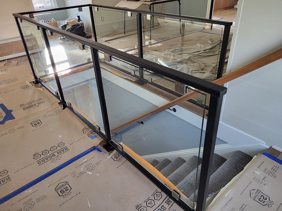 A staircase with glass railing and wood handrail.