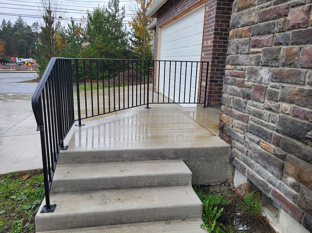 A porch with steps and railings leading to the garage.