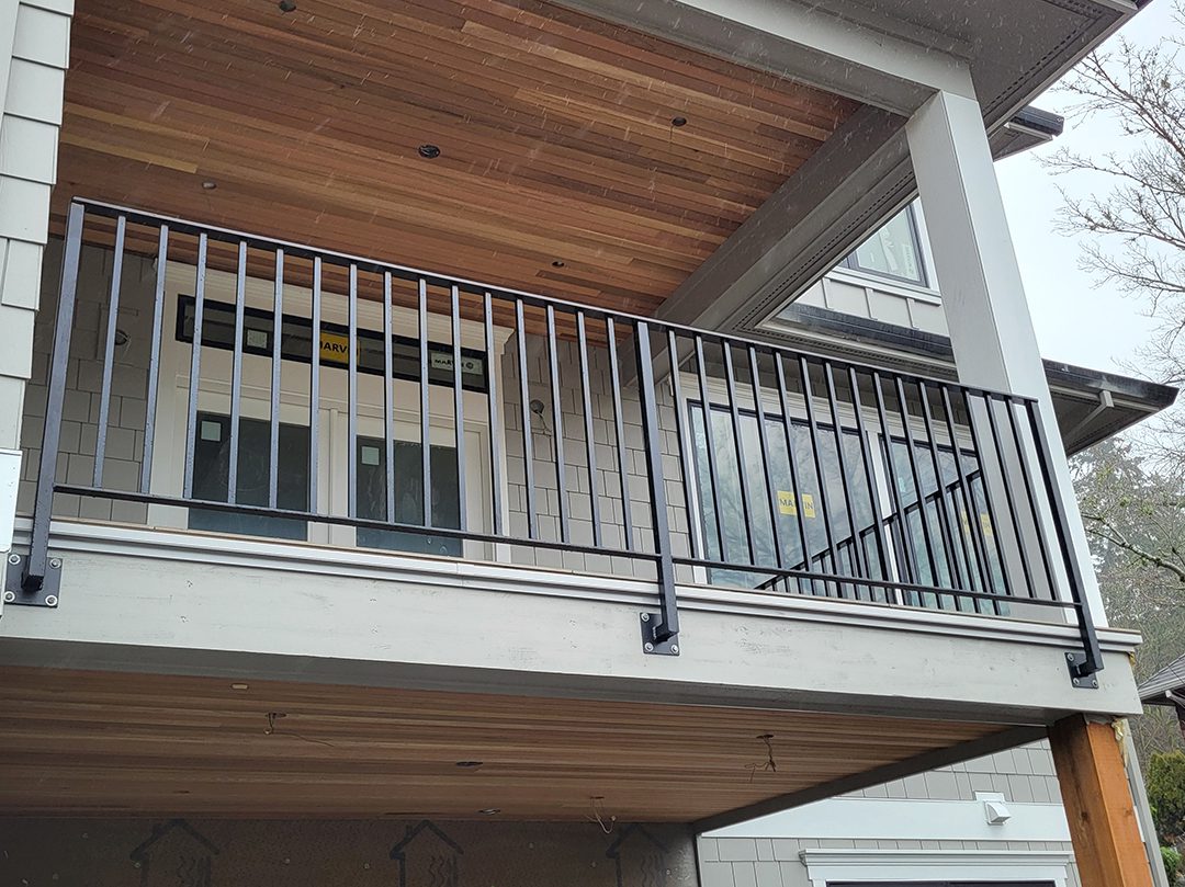 A balcony with metal railing and wood ceiling.