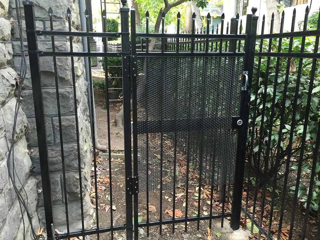 A black metal gate with trees in the background.