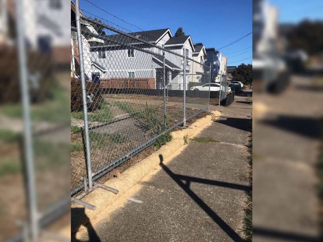 A fence that is in the street next to houses.