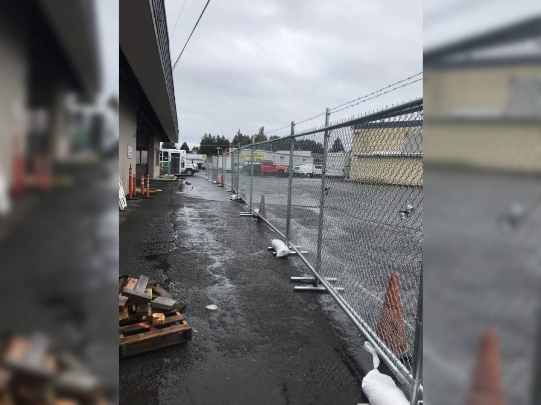 A view of a street with a fence and construction cones.